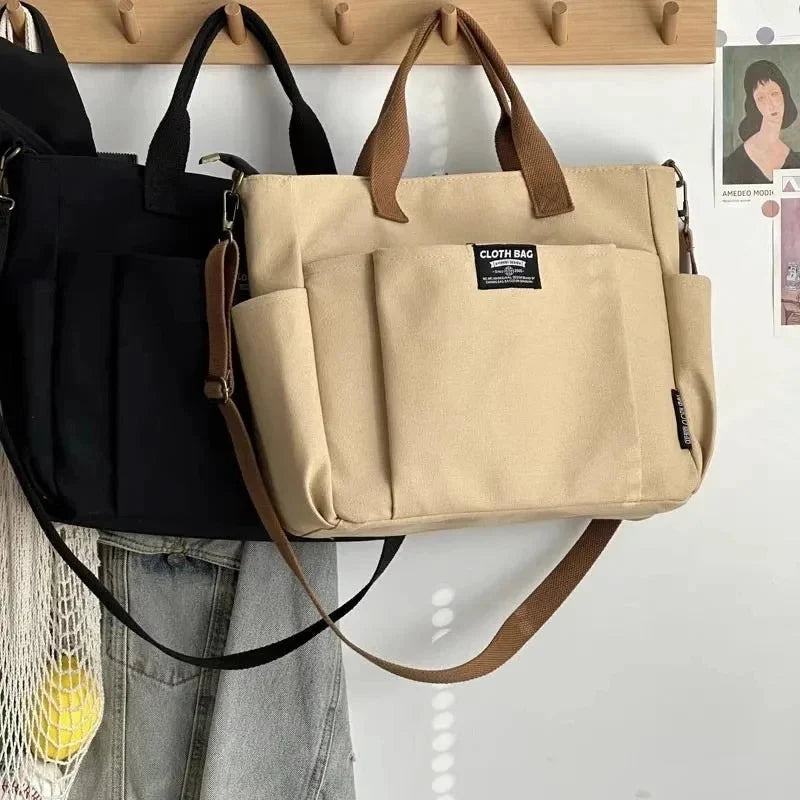 Tan canvas tote bag with two top handles, side zipper pocket, and adjustable crossbody strap