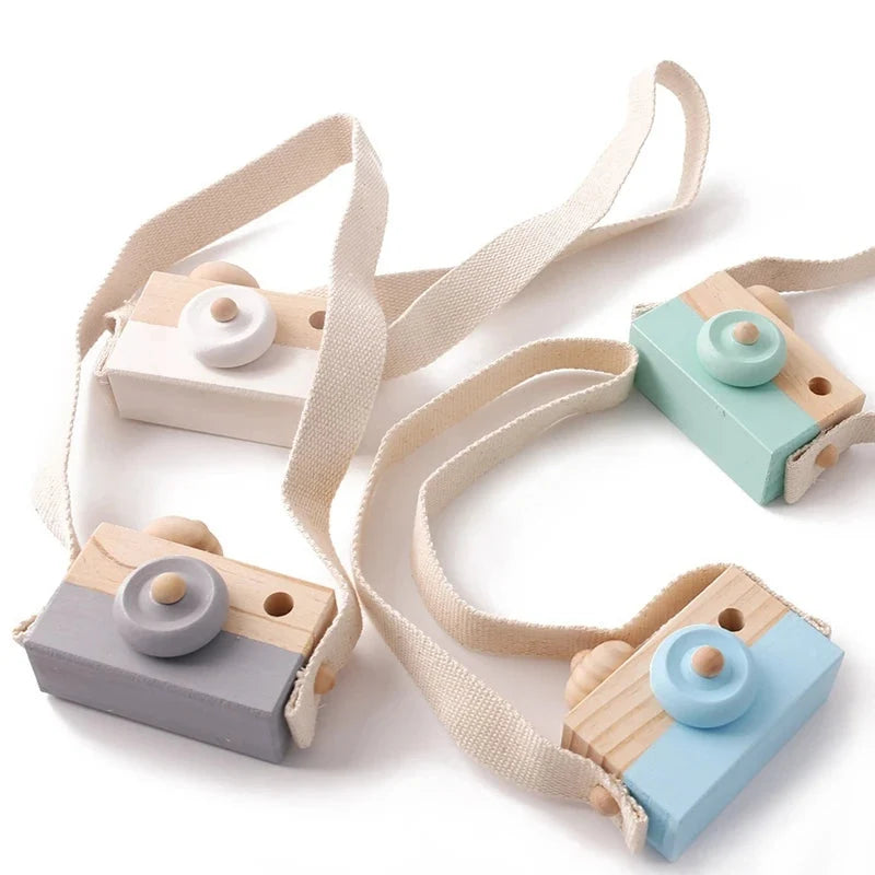 Wooden camera pendant toy assortment with beige straps, featuring grey, blue, and mint bodies