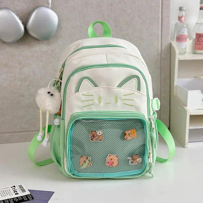 White cat school backpack with green trim; front mesh pocket with small cartoon patches.