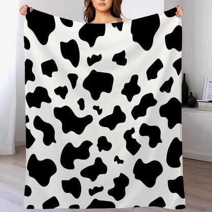 Cow print flannel blanket in black and white, held up for display