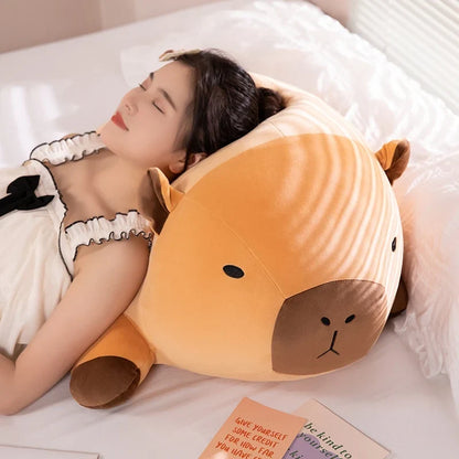 Orange capybara plush pillow with brown face, resting on white bedding