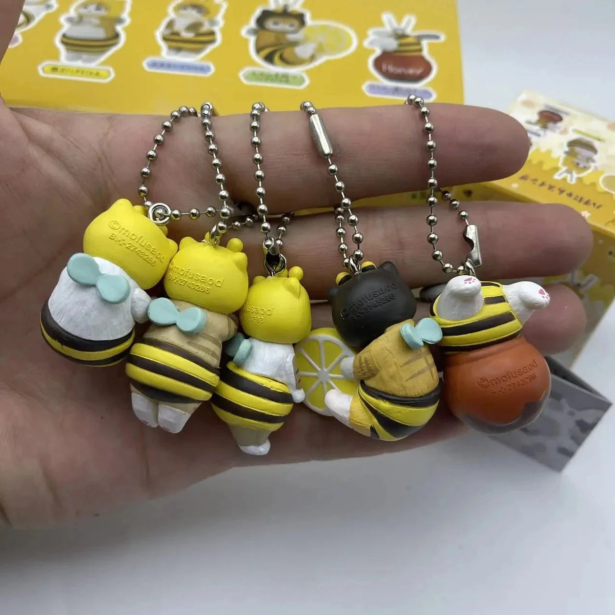 Close-up of twisted egg figure keychains with bee, honey, and cat character charms