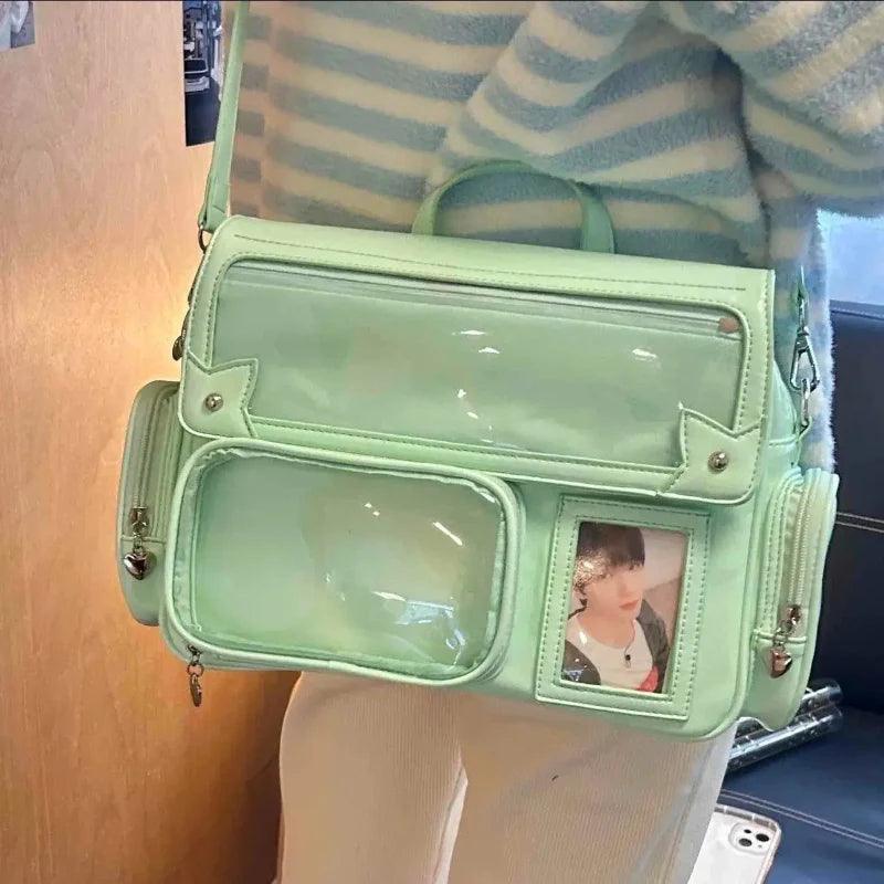 Green ita shoulder bag with glossy finish, clear front panel pocket, and crossbody strap