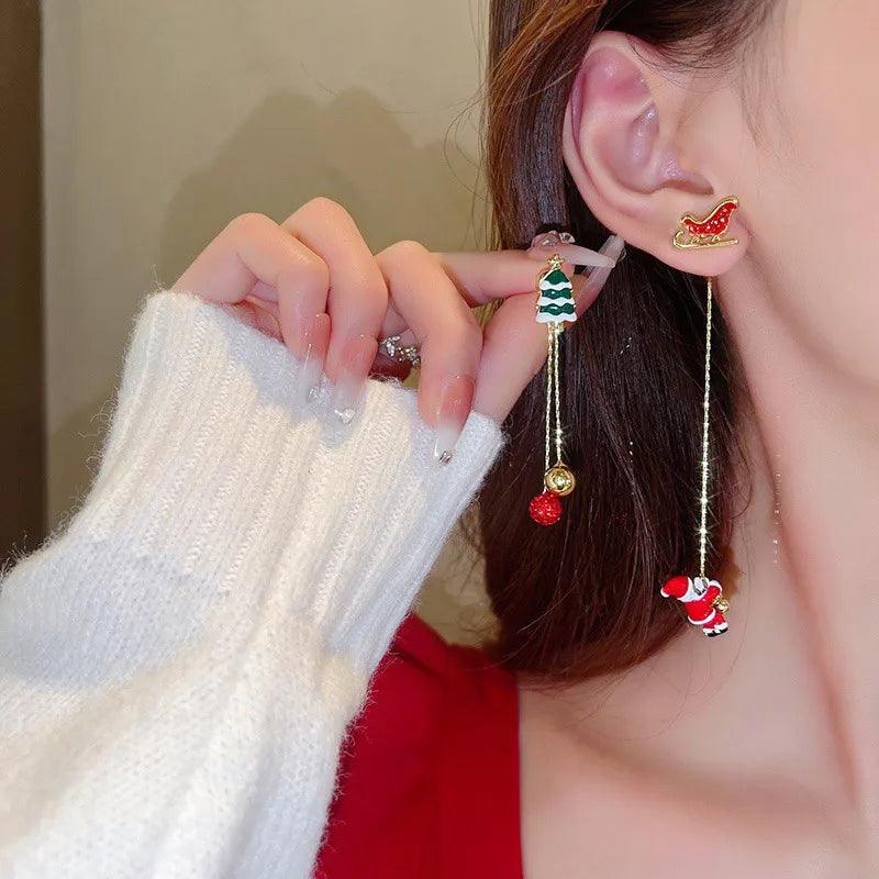 Holiday drop earrings with green tree charm and red Santa charm, dangling on gold chains