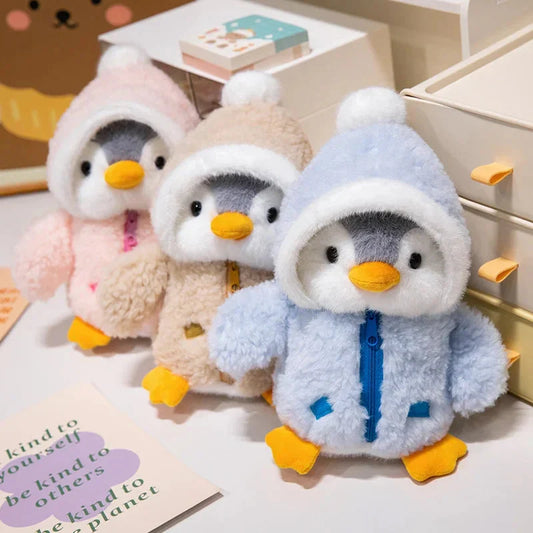 Three plush penguin toys with hooded hats in pink and blue pastel outfits