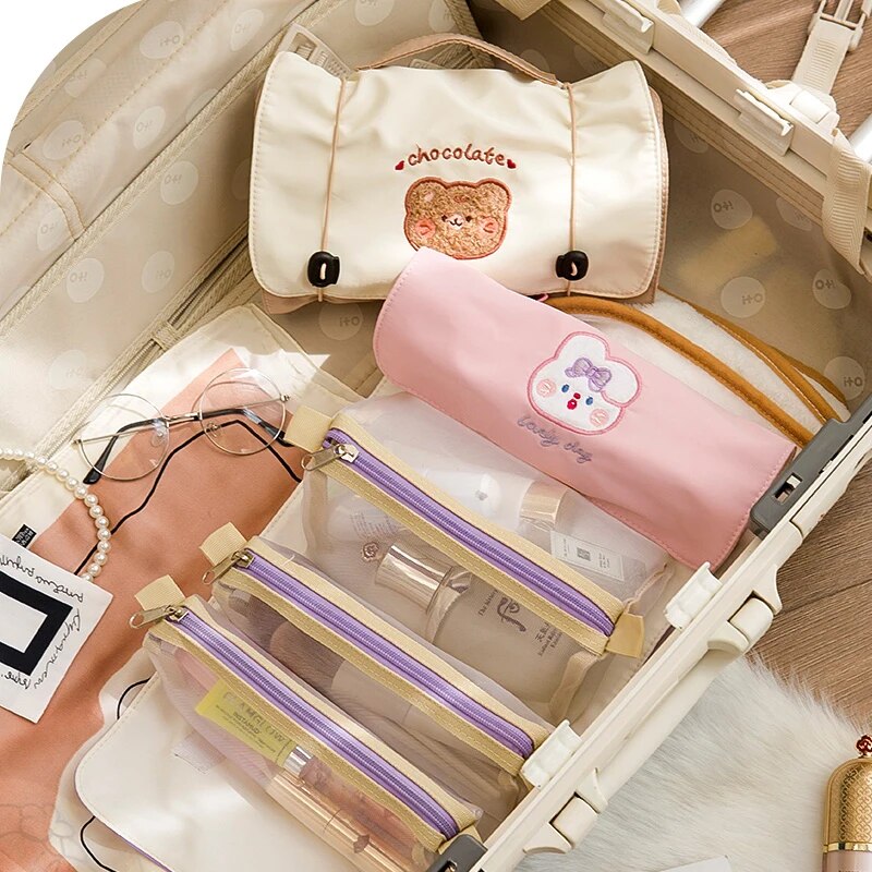 Open roll-up makeup bag with cream and pink pouches, showing multiple clear compartments