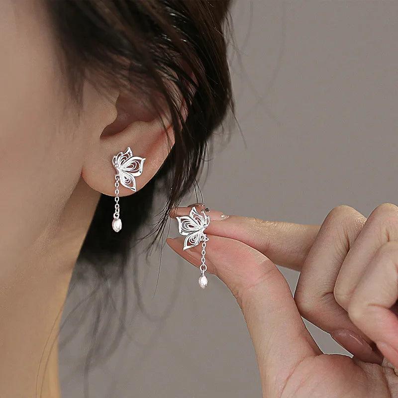 Silver butterfly stud earrings with dangling chain and small teardrop charm