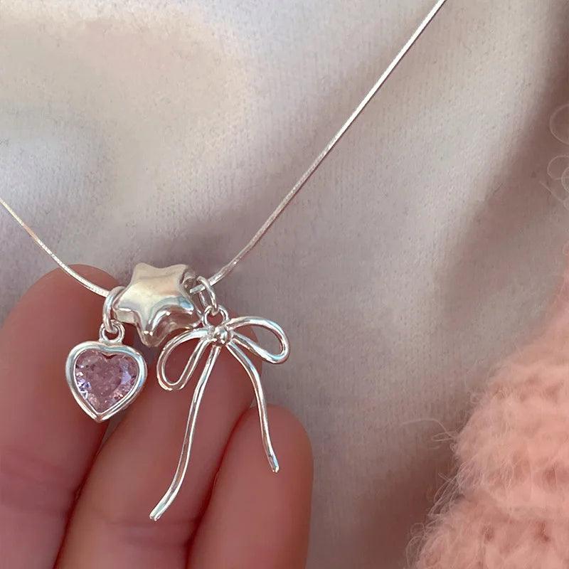 Silver necklace with heart and bow charms, pink heart stone and hanging ribbon strands