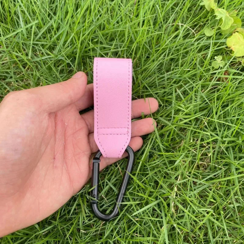 Pink PU stroller bag hanger with black metal S hook held in hand