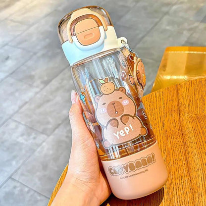 Capybara-themed water bottle side view in hand, clear body, white cap with orange latch