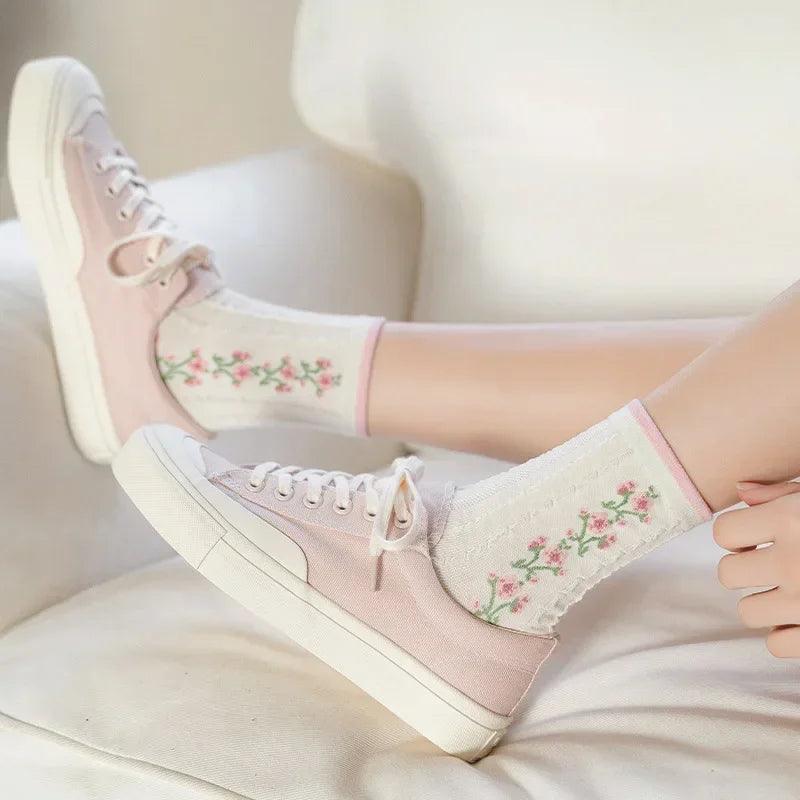Pair of white socks with pink top band and small floral vine patterns