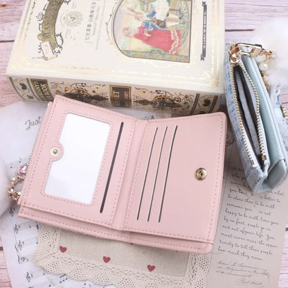 Pink fold-out wallet with card slots and gold-tone button, fabric-wrapped edges