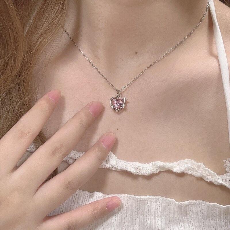 Heart crystal pendant necklace on neckline with silver-tone chain and pink faceted heart