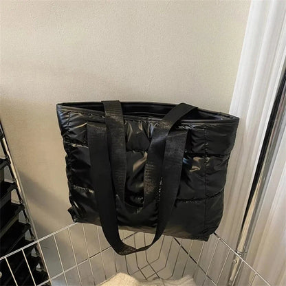 Black quilted tote bag with long handles, open top, puffy quilted body