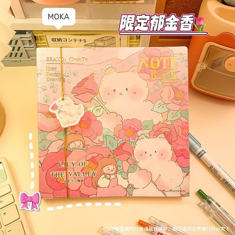 Pink illustrated notebook cover with two rabbits, flowers, and 'LILY OF THE VALLEY'
