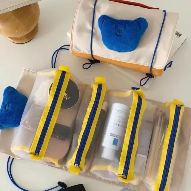Clear roll-up makeup bag with blue cat patch and three yellow-trim zip pouches