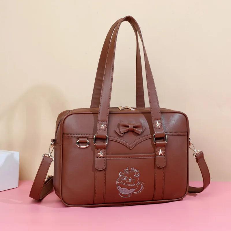 Kawaii messenger bag in brown with front logo patch, bow accent, and dual top handles
