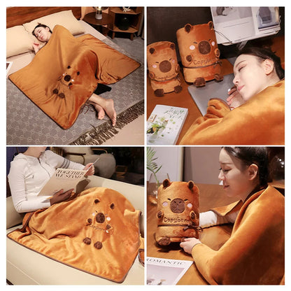Capybara blanket pillow, orange plush rolled design with stitched face on a bed surface.