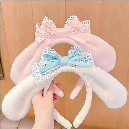 Plush bunny ear headband with pink ears, white band, and blue patterned bow.