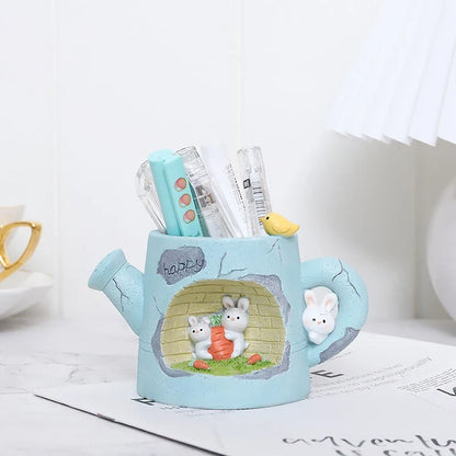 Blue resin watering can planter with bunny garden scene and small succulents