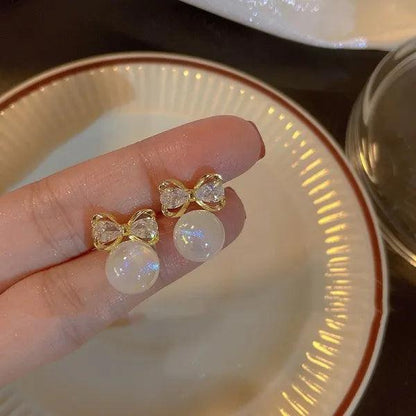 Bow stud earrings with gold frames and opal white teardrop crystals