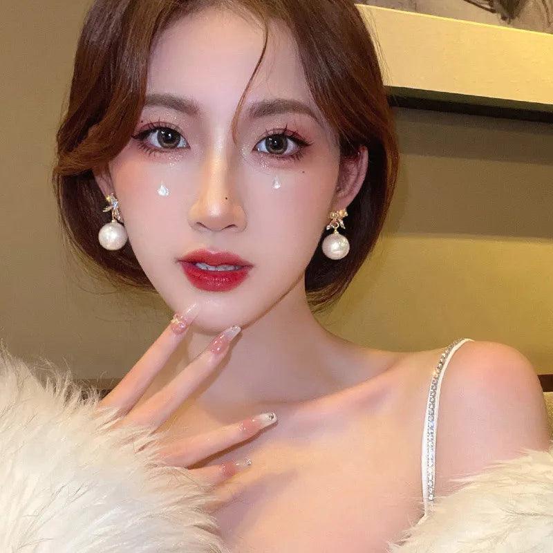 Pearl drop ornament earrings with gold bow and star charms