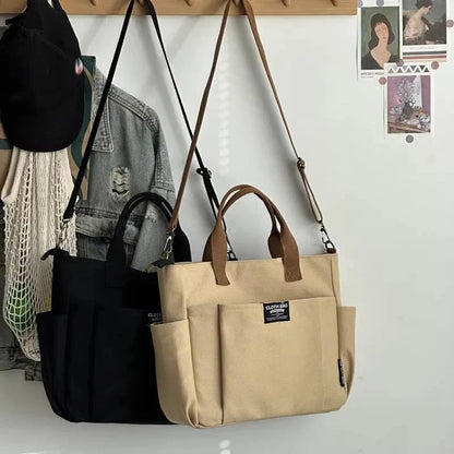 Khaki and black canvas tote bags hanging on hooks, each with crossbody strap and zip pocket