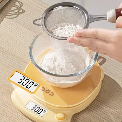 Yellow digital kitchen scale under a sieve above a bowl of flour