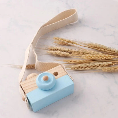 Wooden camera pendant toy with beige strap and light blue front, wooden top and button