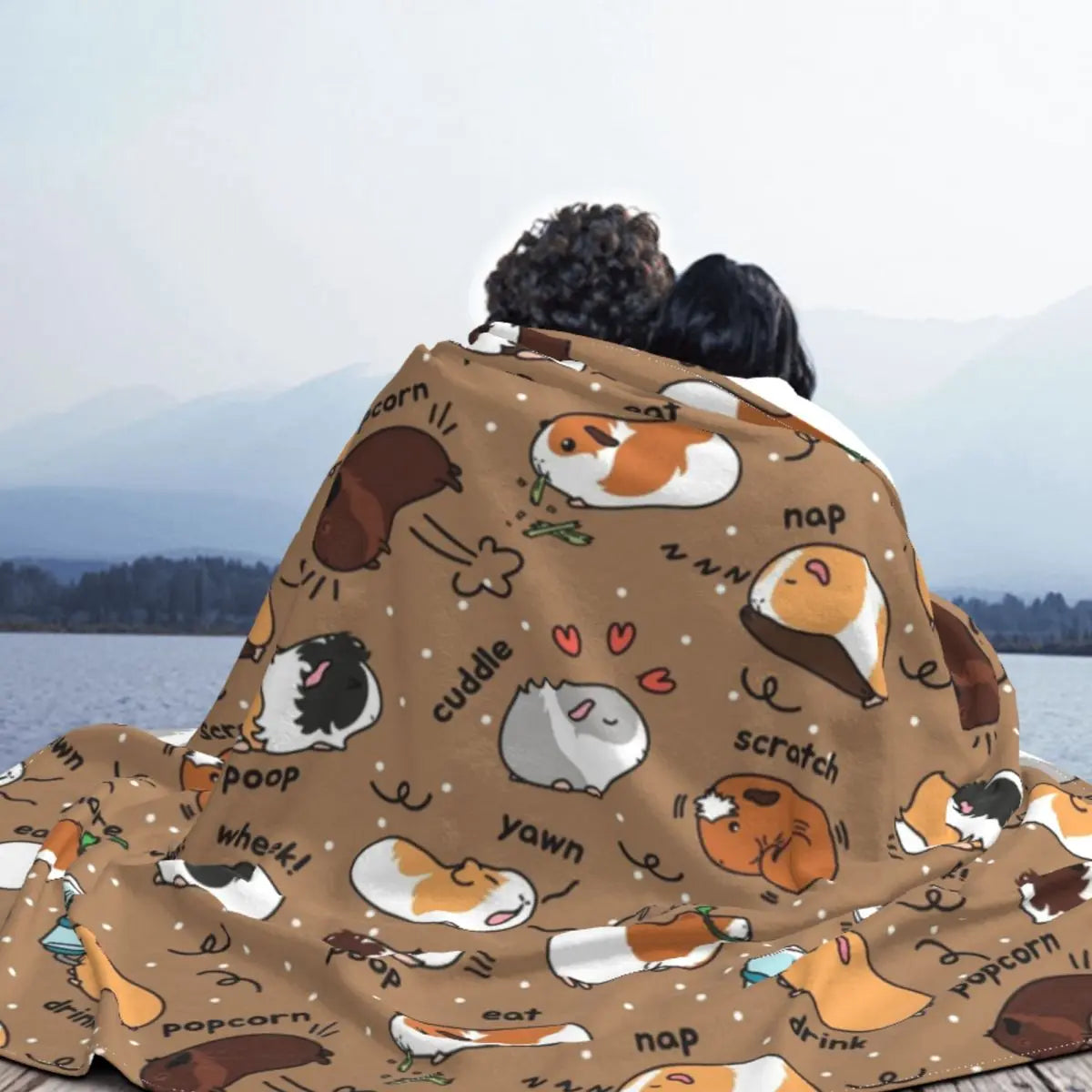 Guinea pig throw blanket with brown base and assorted pet icons, draped over cushions