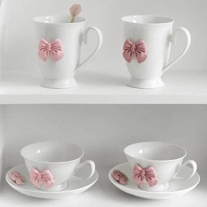 Set of two white tea cups with pink bow ornaments on saucers