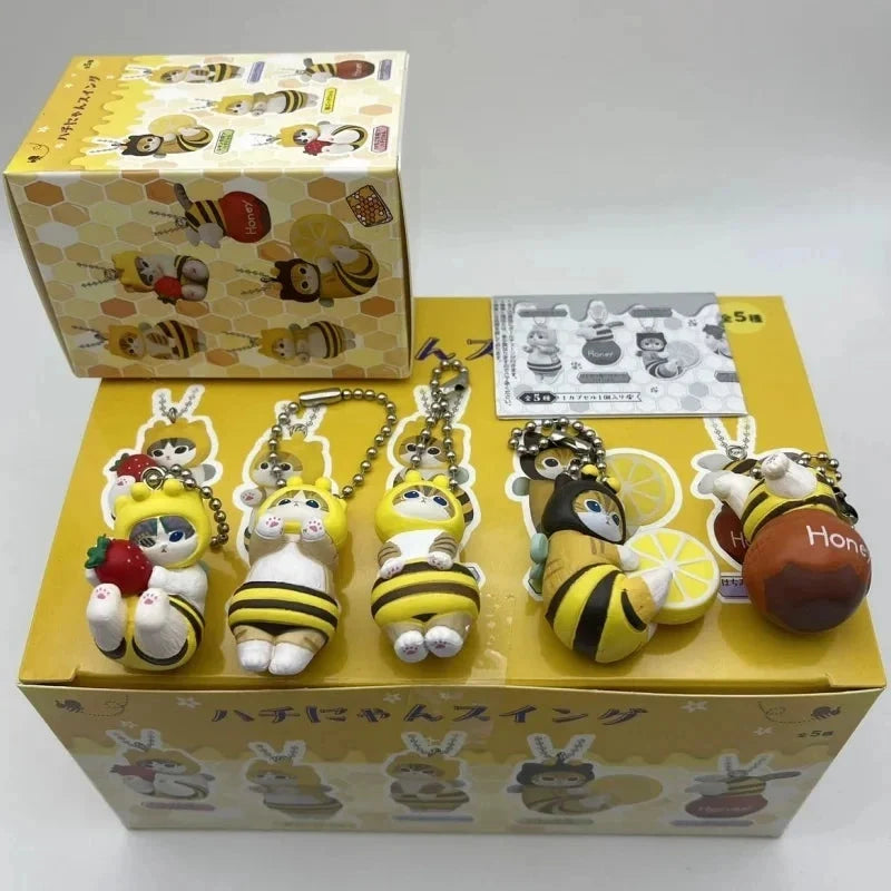 Bee-themed twisted egg anime figure keychains in a display box with multiple charms