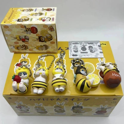 Bee-themed twisted egg anime figure keychains in a display box with multiple charms