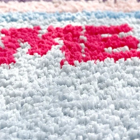 Close-up of shaggy rug fibers with light blue base and bright pink accent rows