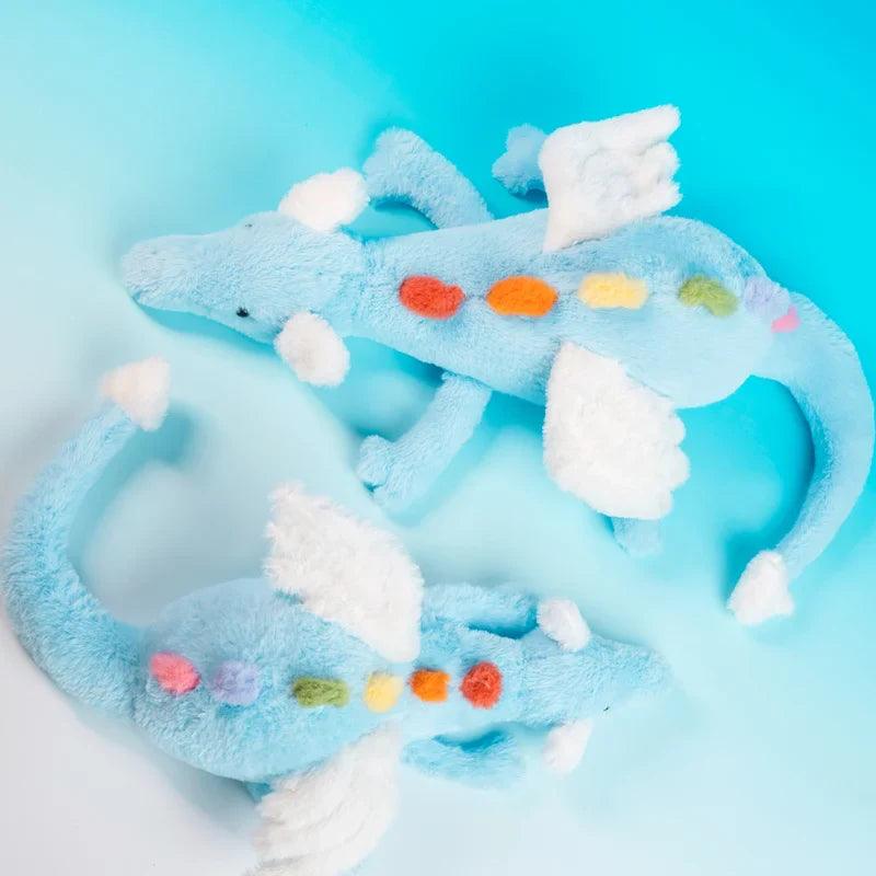 Rainbow dragon plush toy with rainbow dot belly, light blue and white cloud-like accents