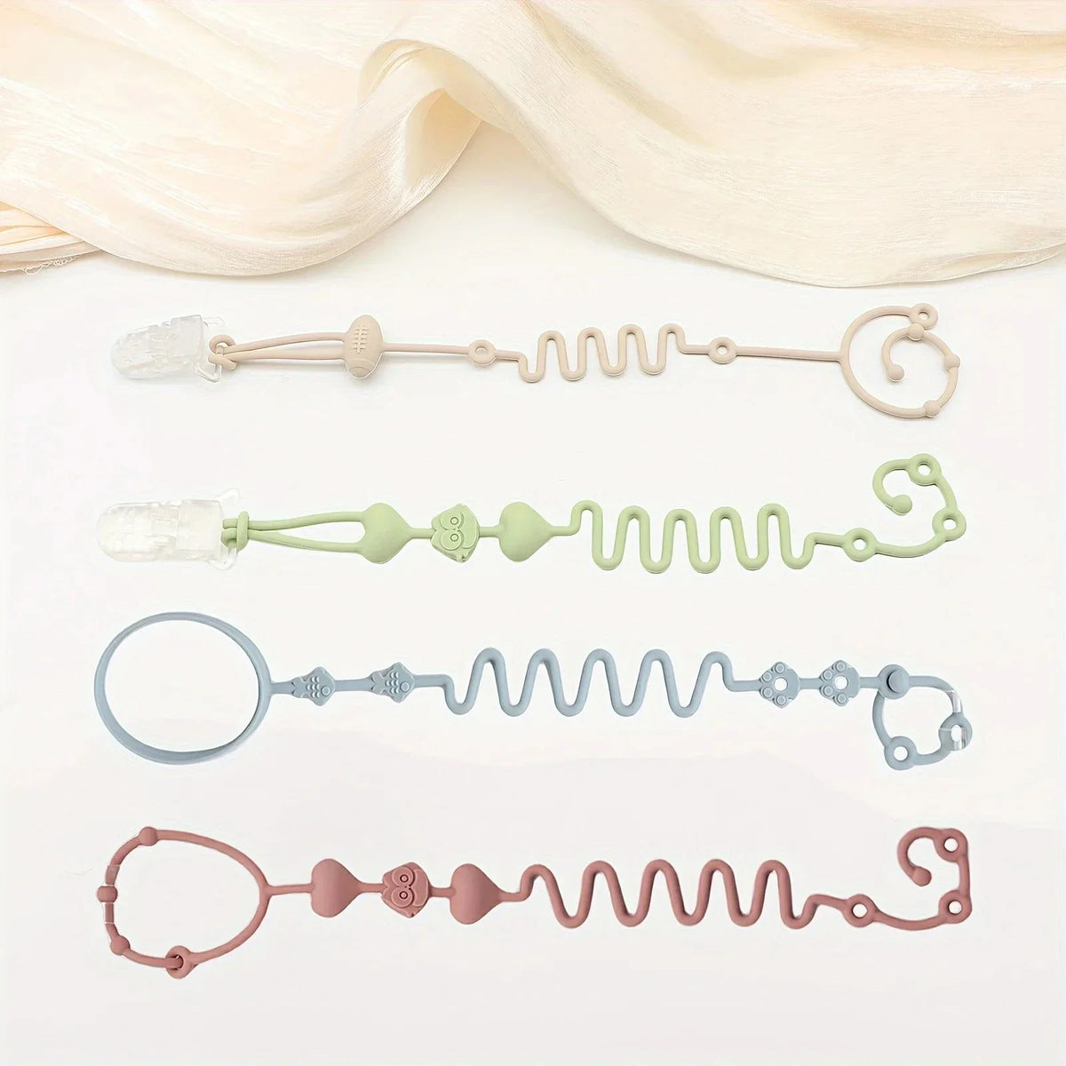 Flat lay of four silicone pacifier chain toys in pastel beige, green, blue, and pink