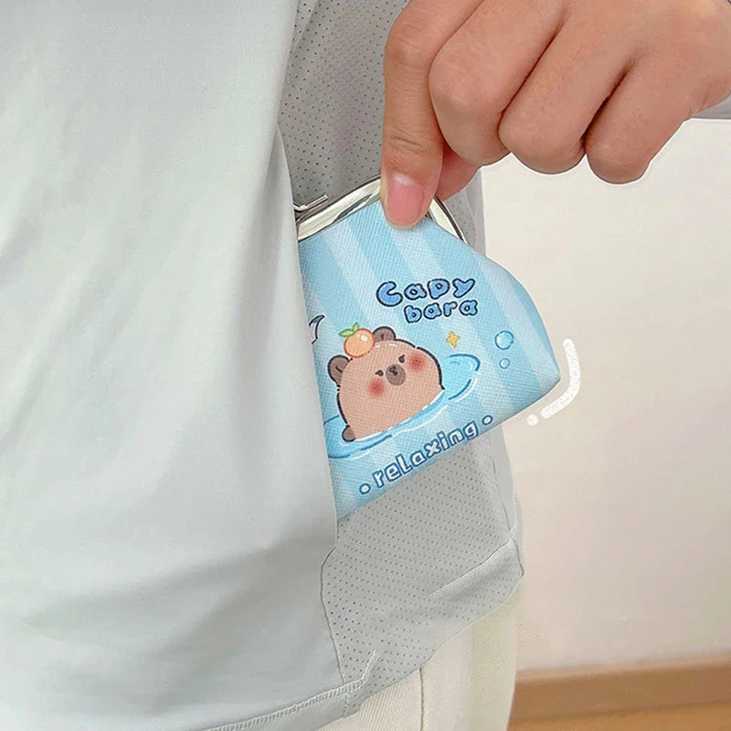 Blue capybara coin purse with metal kiss-lock clasp, held in hand