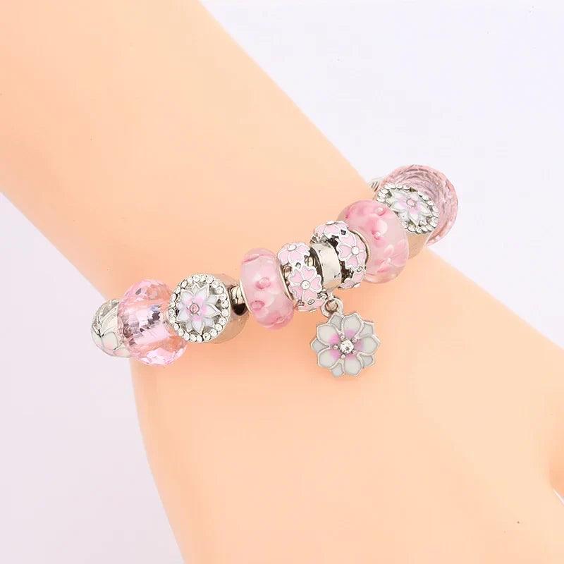 Pink charm bracelet worn on wrist, clear and pink beads with flower charms
