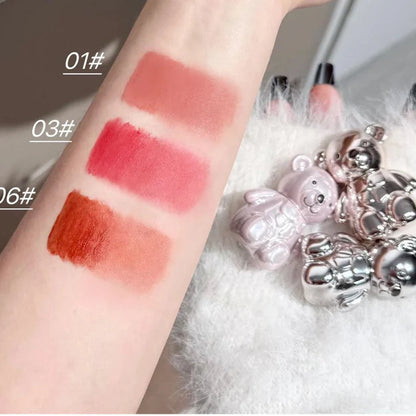 Swatches of lip or cheek shades in peach, red, and orange on skin with compact