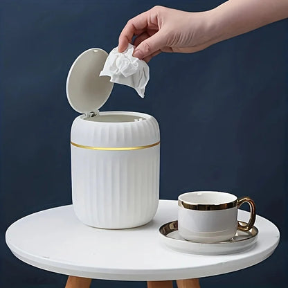 Mini desktop trash can with lid open, hand lifting tissue from top opening