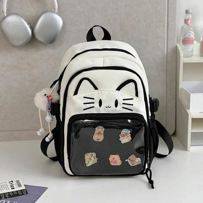 White cat school backpack with black trim; clear front pouch with cartoon food patches.