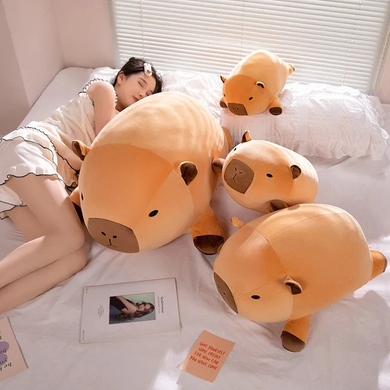 Set of orange capybara plush pillows with brown faces on a bed