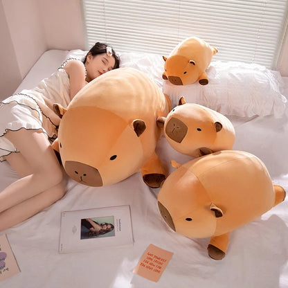 Set of orange capybara plush pillows with brown faces on a bed