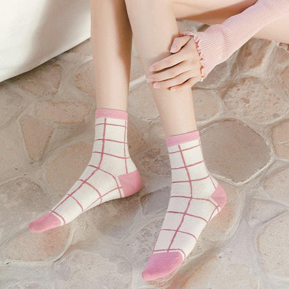 Plaid socks worn on feet, white with red grid and pink toe