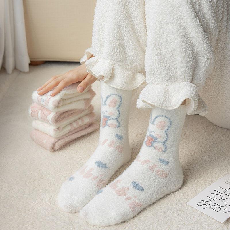 Bunny socks on feet with white fuzzy texture and pastel bunny paw designs on the cuffs.