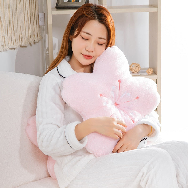 Pink plush cherry blossom pillow with petal shapes and embroidered blossom stamens.