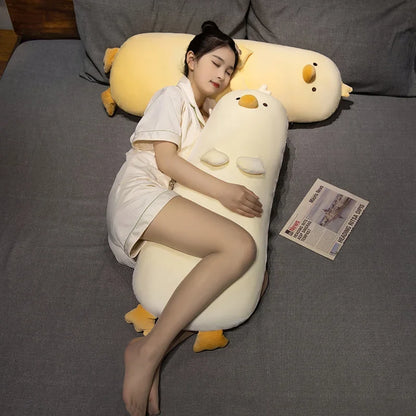 Long yellow chick plush pillow with stitched eyes, beak, and small wing patches