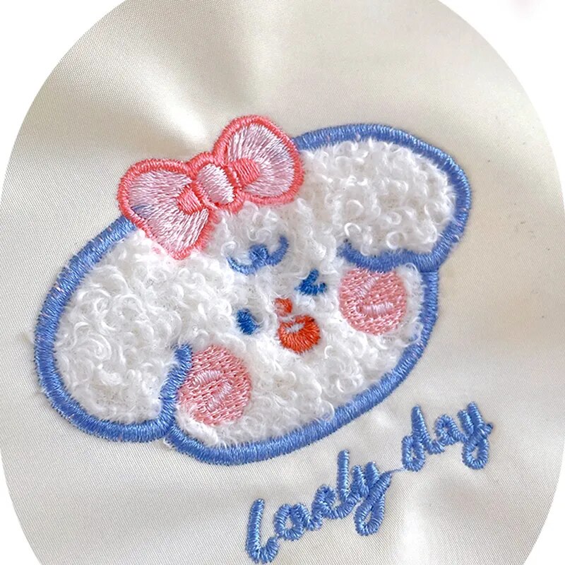 Embroidered cute bear face patch with red bow and blue outline on light fabric