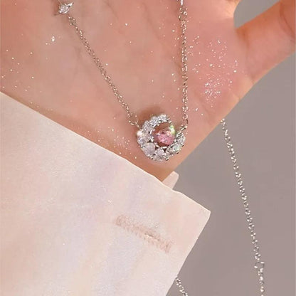 Heart zircon pendant with pink center stone on a thin silver chain, worn near neckline