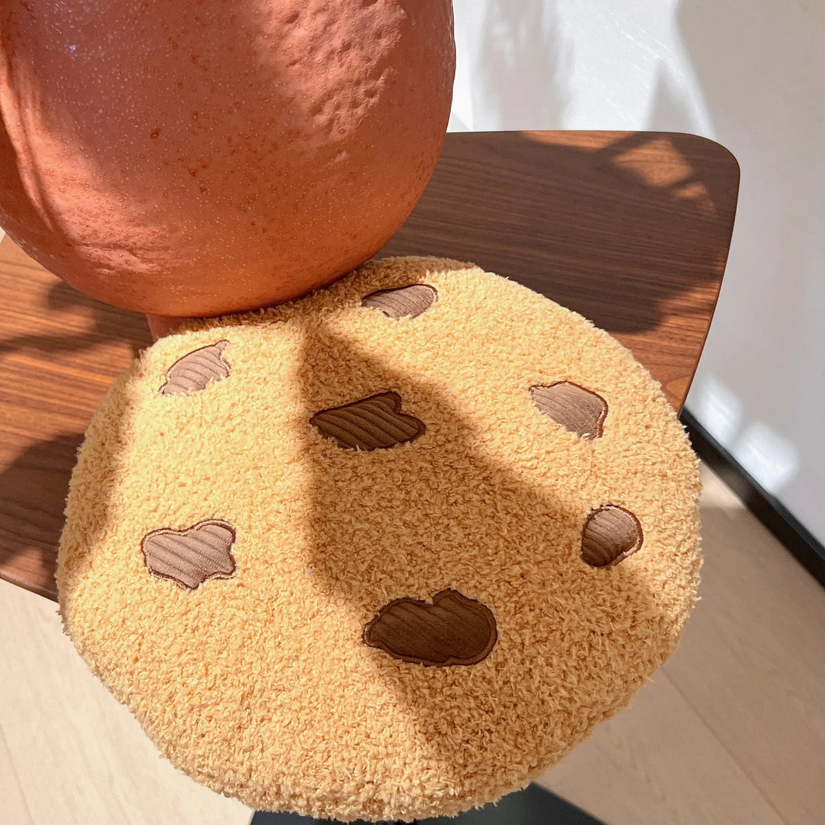 Tan cookie plush pillow with brown stitched chocolate-chip shapes
